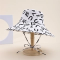 White bucket hat with black graffiti print and chin strap shown on a wooden stand - Letter Style / White