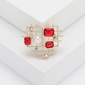 Hohlherz-Brosche in Gold mit roten Kristallen und Perle auf weißen geometrischen Stufen - Rot