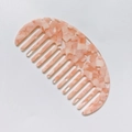 Primer plano del peine de acetato rosa con dientes anchos y elegante estampado de carey - Rosa