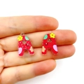 Close-up of red acrylic letter A pendants with glitter finish and floral cartoon patterns - Letter A
