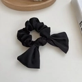 Elegant black fabric scrunchie with a ribbon bow detail on white minimalist background - Black Satin Bow