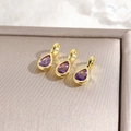 Detailed view of three teardrop pendants with purple zircons and 18k gold plating - Purple