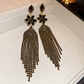 Dettaglio orecchini a fiore scuro con strass neri e lunghe catenine pendenti a nappa - Stile Nappa Oro Nero (Ago d'Argento)