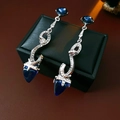 Macro shot of silver snake-shaped earrings with blue gemstones on leather - 60# Silver Pin-Silver-Blue