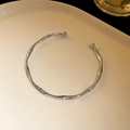 Silberfarbenes gehämmerte Edelstahlarmband mit Kugelenden auf einer Keramikplatte - Gedrehter Hammerschlag-Stil / Silber