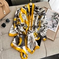 Écharpe en soie élégante à imprimé jaune et gris sur un canapé avec des accessoires - Jaune