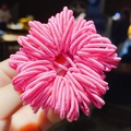 Hand holding a flower-shaped pink hair tie made of tiny elastic rubber bands - 24# Pink Approx 100Pcs