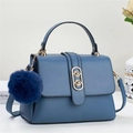 Close-up of blue lychee leather handbag featuring golden hardware and a fluffy charm - Blue