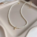 Minimalist pearl necklace with tiny white pearls and a small gold bead pendant detail - Round Bead Pearl Style