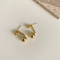 Dettaglio di orecchini a doppia sfera dorati in argento S925 su decorazione minimalista - Bottone a Doppia Sfera / Oro