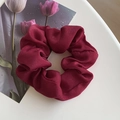 Deep red satin silk scrunchie with elegant pleats on a minimalist white surface - Red