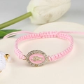 Detail of pink woven bracelet featuring a gold Madonna charm with white crystals - Pink