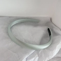 Detail of light green satin headband featuring a black handmade textile label on the side - Lake Blue