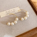 Detail of C-shaped gold earrings with five baroque pearls on linen and wood - Ear Hook-White