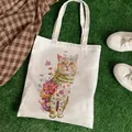 White canvas tote bag featuring an artistic cat and flower print on green grass - C5 Grassland Cat