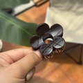 Détail d'une pince à cheveux fleur marron foncé de 5 cm avec une finition en résine brillante - 5cm / Chocolat