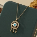 Détail du collier attrape-rêves Mauvais Œil doré avec plumes sur un écrin à bijoux - A33-or