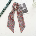 Detailed macro view of floral print scrunchie with long ribbons on artistic white backdrop - Chiffon Ribbon / Colorful Floral
