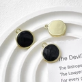 Detail view of round gold enamel charms on a textured tray for DIY jewelry making - Black
