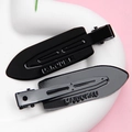 Close-up of black seamless hair clips in glossy and matte finish on white ceramic base - Black - Glossy with Letters