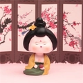 Cute resin ancient style girl figurine in yellow and green dress on a floral background - Playing Chess