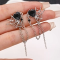 Gothic silver earrings featuring black heart gems and spiderweb chains held by hand - Spiderweb Black Heart Tassel (G-593) / White Gold