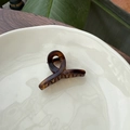 Close-up of mini tortoiseshell hair claw clip with amber texture on white ceramic plate - 5.5cm Butterfly Buckle / Matte Light Tortoise