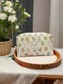 Floral quilted toiletry bag in cream with botanical patterns on a wooden tray - Green Floral with Label