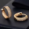 Macro view of gold hoop earrings with three rows of pavé set white cubic zirconia - Triple Row Zirconia / Gold