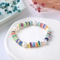 Detail eines handgefertigten Regenbogen-Polymer-Armbands mit Süßwasserperlen und Goldperlen - Mehrfarbige Ton Perle