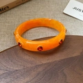Orange acrylic bangle with red gemstones and marble texture in a retro vintage style - Orange