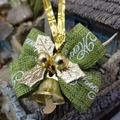 Dettaglio di un fiocco verde con campanellino dorato e foglie di agrifoglio natalizio - Stile di Natale 2
