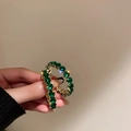 Primo piano di orecchini a cerchio dorati a C con scintillanti pietre di zircone verde - Tondo Verde Smeraldo Oro