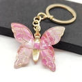 Macro view of gradient pink resin butterfly keychain with elegant golden metal framing - Rose Red