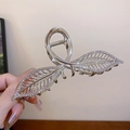 Gros plan détaillé d'une pince à cheveux argentée en forme de feuille avec diamants - Feuille creuse argentée