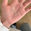 Silver twisted double-loop pendant necklace shown in hand for size and style - Double Ring Twisted Hollow Pendant Necklace (XL2193)