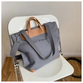 Grey canvas tote bag with brown leather handles and a grey shoulder strap on a chair - Gray