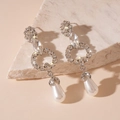 Macro detail of silver floral teardrop earrings with crystals and faux pearls on marble - Flower Geometric Pearl Drop / Silver