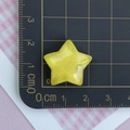 Macro shot of 2cm yellow glitter resin star accessory on a centimeter grid mat - Glitter Yellow Star