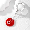 Macro view of a red glass Evil Eye charm keychain with a silver ring on a white base - Red Glass Eye