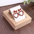 Bamboo jewelry tray with 36 slots featuring red heart rhinestone stud earrings with gold bows - 1 Slot - White PU