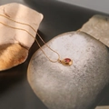 Dettaglio macro del ciondolo ovale in pietra rossa incastonato in oro su roccia naturale - Zirconia Rossa (XL079/XL080)
