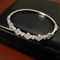 Detalle de brazalete de trébol plateado con circonitas sobre joyero de cuero - Bangle / Plateado