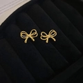 Nahaufnahme goldener Schleifen-Ohrstecker in einer schwarzen Samt-Schmuckschatulle - Gold