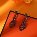 Gothic punk skull hand earrings in gun black finish on vibrant orange background - Gun Black Skull Hand Shape Earrings (29) / Gunmetal