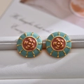 Nahaufnahme der Emaille-Kamelien-Ohrstecker mit Goldplattierung und Blumendetails - Seeblau