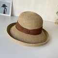 Detailed texture of hand-woven straw hat with elegant brown fabric ribbon decoration - Coffee