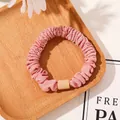 Detailed view of pink pleated satin scrunchie with matte button on a wooden tray - Tencel Velvet Pink