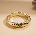 Primer plano del brazalete de metal dorado ondulado con acabado brillante sobre fondo neutro - Círculo Plisado Dorado