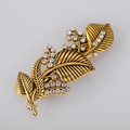 Macro-opname van een vintage gouden blad haarklem versierd met witte glanzende steentjes - Antiek Goud